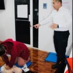 Instructor de primeros auxilios enseñando reanimación cardiopulmonar (RCP) a una terapeuta de Centro LUA con un maniquí de práctica