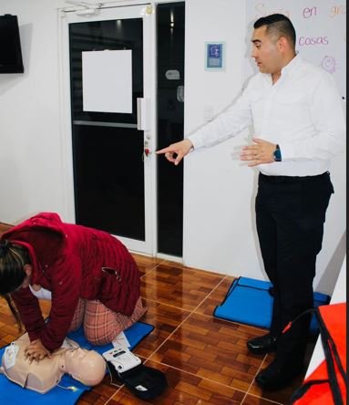 Instructor de primeros auxilios enseñando reanimación cardiopulmonar (RCP) a una terapeuta de Centro LUA con un maniquí de práctica